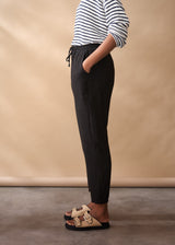 Women wearing a striped jumper with black tapered linen trousers
