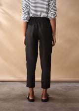 Women wearing a striped jumper with black tapered linen trousers