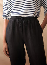 Women wearing a striped jumper with black tapered linen trousers