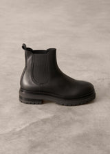Black Chelsea boot on a gray concrete surface