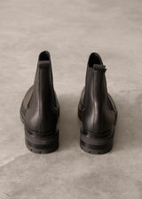 Pair of black Chelsea boots on a gray concrete surface