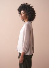Woman wearing a pale lilac satin blouse against a beige background