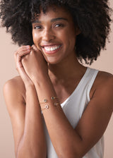 Woman wearing gold bracelets on a beige background