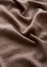 A close-up of draped brown knit fabric with soft folds and a fine ribbed texture.