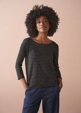 Woman wearing a striped gold and black top against a beige background