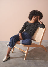 Woman wearing a striped gold and black top against a beige background