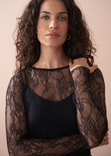 Woman wearing a black lace top against a beige background