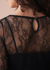 Black lace garment with floral patterns on a neutral background