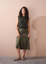 Woman wearing a green sleeveless top and skirt against a beige background