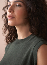 Woman wearing a green sleeveless top against a neutral background