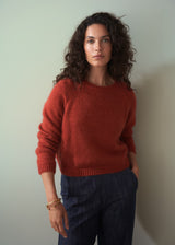 Woman wearing a red sweater against a plain background