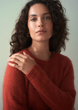 Woman wearing a red sweater against a light green background