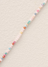 A long beaded necklace with small multicoloured beads arranged in an irregular, organic shape, displayed on a plain off-white background.