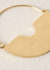 Gold half-circle pendant on a light beige background