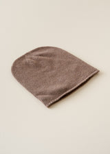 A ribbed knit beanie hat in a muted taupe-brown color, displayed flat against a solid, warm off-white background.