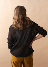 Person wearing a black top and mustard pants against a beige background