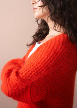 Person wearing a red sweater against a beige background