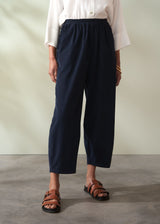 Person wearing navy corduroy barrel leg trousers and brown sandals on a plain background