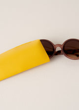 Sunglasses with a yellow case on a light beige background