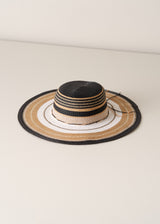 Straw hat with black, beige, and white stripes on a light beige background