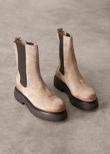 Pair of beige Chelsea boots with black soles on a gray background