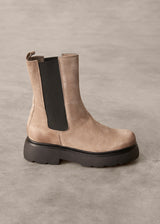 Brown Chelsea boot with black sole on a gray background