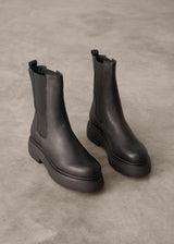 Pair of black Chelsea boots on a gray concrete surface