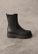 Black Chelsea boot on a gray concrete floor