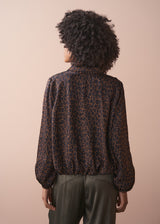 Person wearing a leopard print bubble hem shirt with a plain background