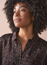 Woman wearing a leopard print bubble hem shirt against a beige background