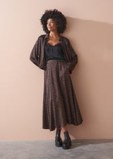 Woman wearing a leopard bubble hem shirt outfit against a beige wall