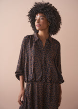 Woman wearing a leopard print bubble hem shirt against a beige background