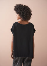 Person wearing a black top and plaid barrel leg trousers against a beige background