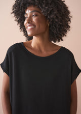 Woman wearing a black t-shirt against a beige background