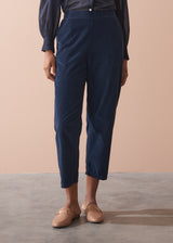 Person wearing navy corduroy trousers and brown shoes on a beige background