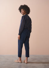 Woman wearing a navy blue outfit against a beige background