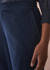 navy corduroy trousers with a person wearing them against a neutral background