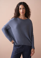 Woman wearing a grey sweater against a beige background