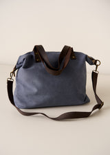 Blue bag with brown leather handles on a beige background