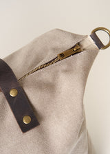 Beige tote bag with brown leather straps on a light beige background