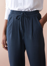 dark grey jersey trousers with drawstring waist on a beige background