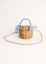 A round wicker basket with a blue gingham handle