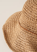 Close up of floppy straw hat against a beige background