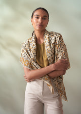 Woman wearing a patterned scarf over her shoulders against a plain background
