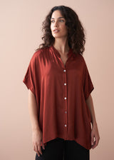 Woman wearing a rust shirt against a beige background