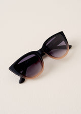 Black cat-eye sunglasses on a light beige background