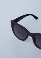 A pair of oversized cat eye sunglasses with black frames and blue lenses