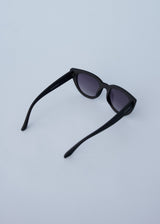 A pair of oversized cat eye sunglasses with black frames and blue lenses