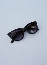 A pair of oversized cat eye sunglasses with black frames and blue lenses