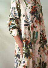 Close-up of pocket detail on a woman's v-neck floral midi dress, against a plain background